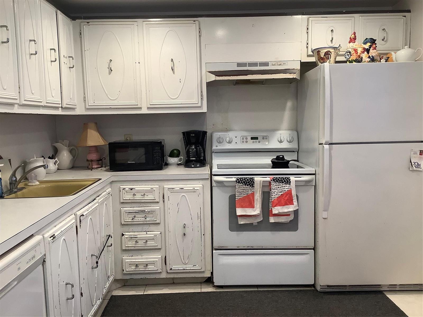 A kitchen features white cabinets, a white stove, a white refrigerator, and a gold sink — 2300 NE 1st Lane # 107, Boynton Beach FL 33435, BOYNTON BEACH, FL