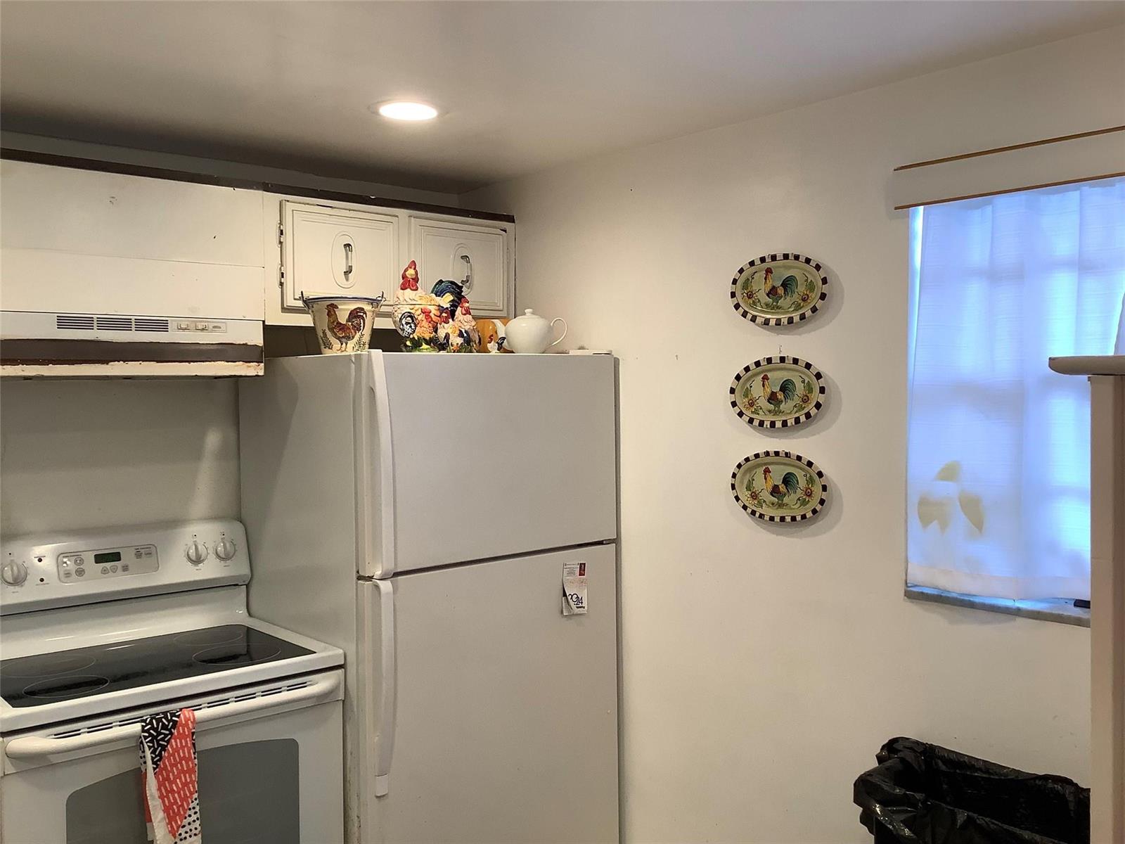 A kitchen features a white stove, a refrigerator, and rooster-themed wall decor — 2300 NE 1st Lane # 107, Boynton Beach FL 33435, BOYNTON BEACH, FL