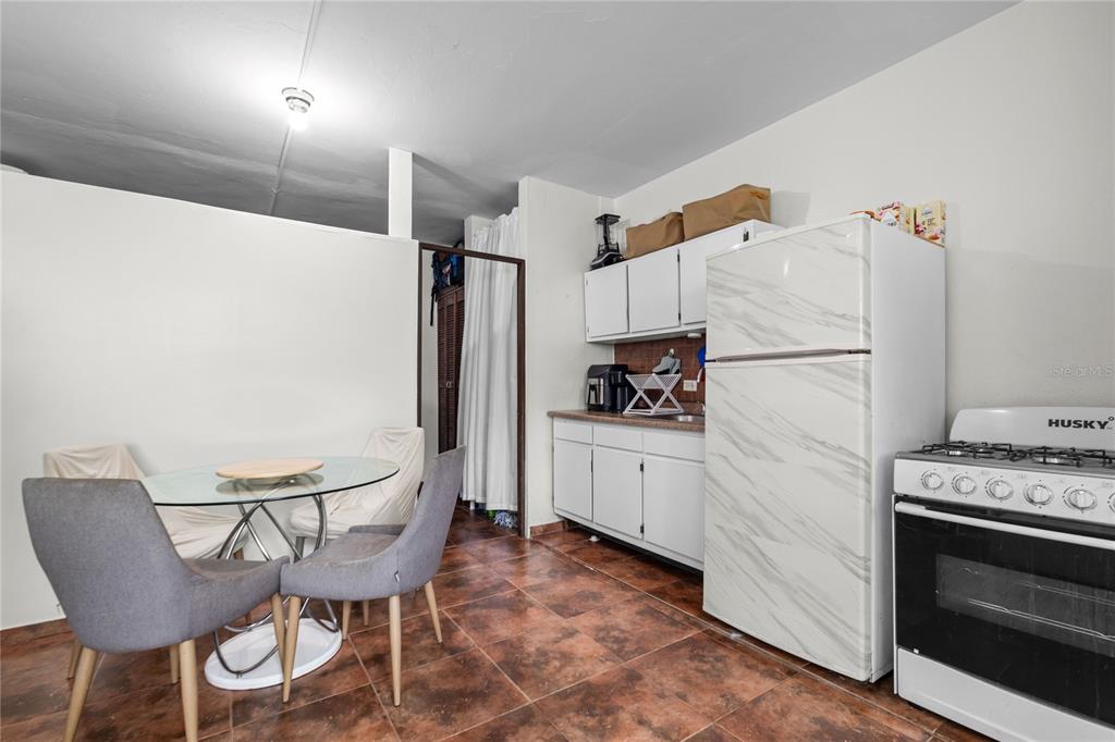 A kitchen and dining area features a glass table, grey chairs, and white cabinetry — 228 CALLE 25, GUAYNABO, PR