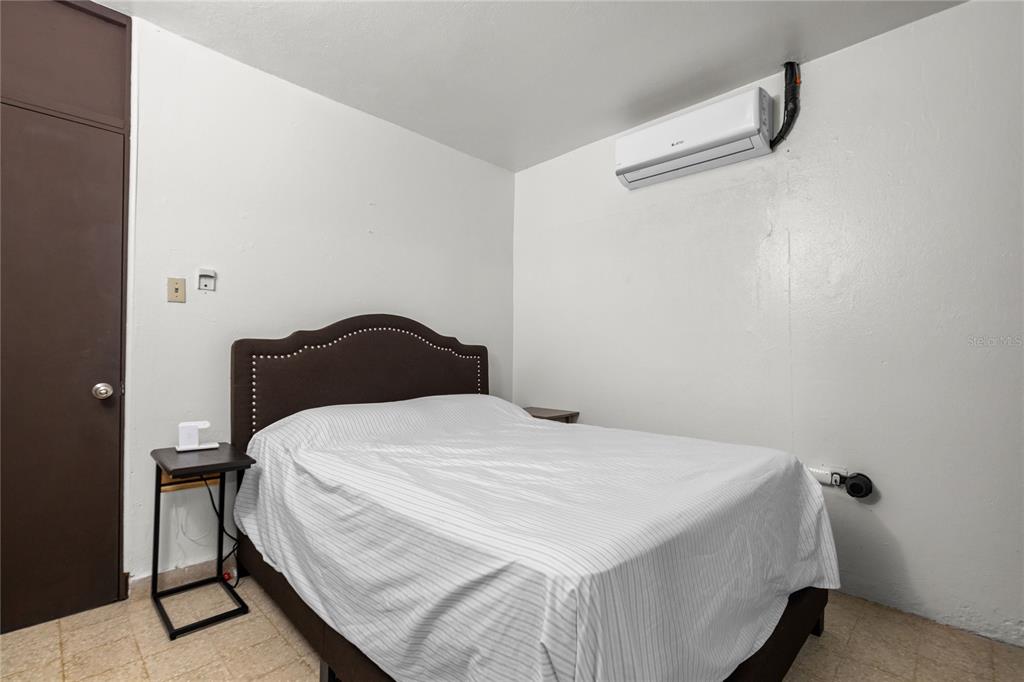 A bedroom features a bed with a dark headboard, a small side table, and a wall-mounted AC — 228 CALLE 25, GUAYNABO, PR