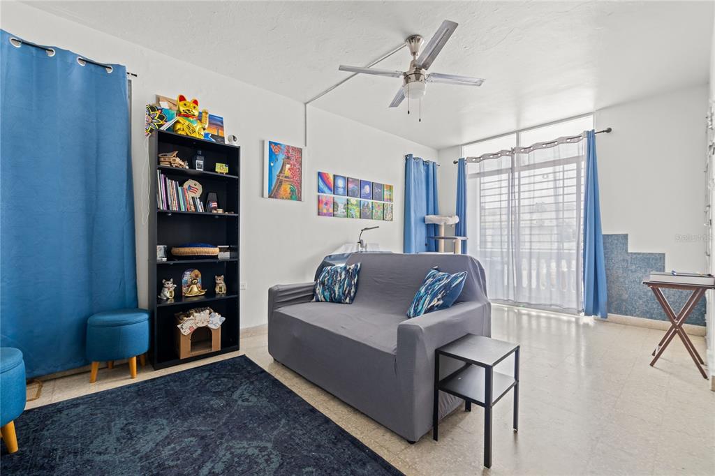 A living room features a gray sofa, a black bookshelf, blue curtains, and a ceiling fan — 228 CALLE 25, GUAYNABO, PR