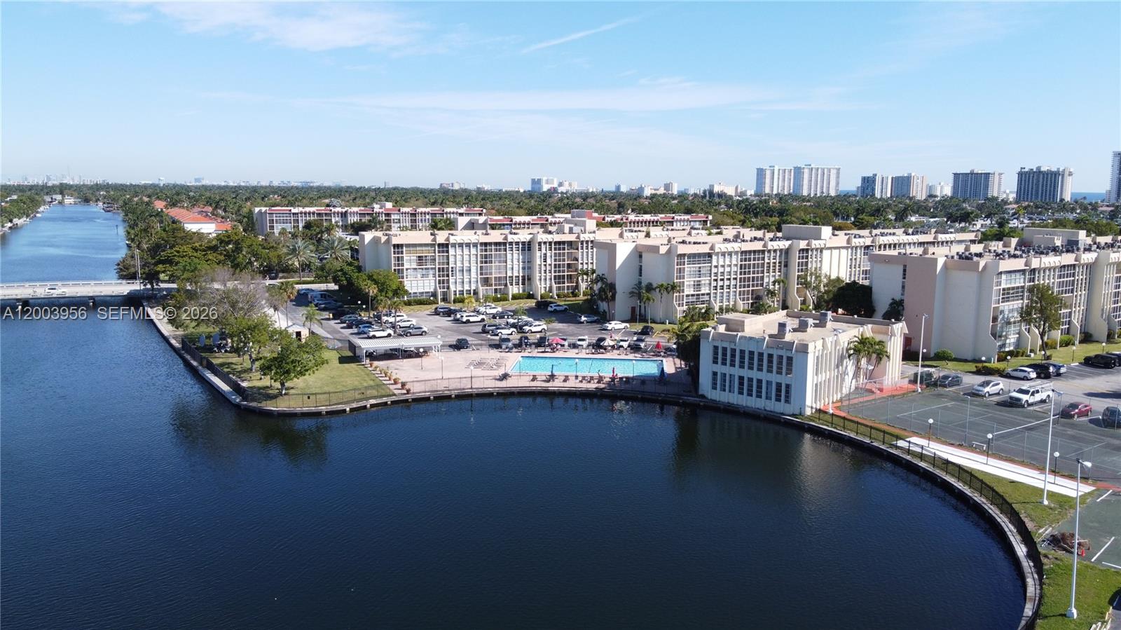 An aerial view shows a residential complex with a swimming pool beside a canal — 851 Three Islands Blvd # 411, Hallandale Beach FL 33009, HALLANDALE BEACH, FL