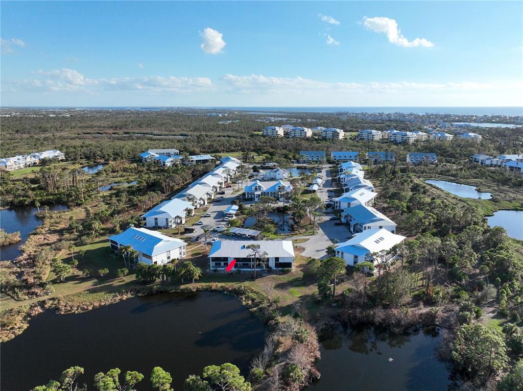 An aerial view shows a multi-story residential complex with white buildings and metal roofs — 6800 PLACIDA ROAD UNIT 268, ENGLEWOOD, FL