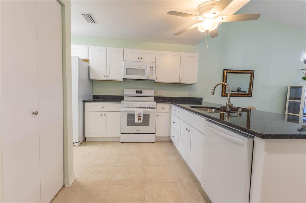 A kitchen features white cabinets, white appliances, dark countertops, and light-colored tile flooring — 6800 PLACIDA ROAD UNIT 268, ENGLEWOOD, FL
