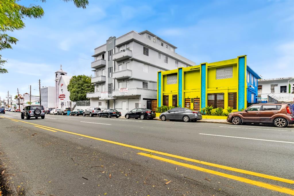 A street-level view shows a grey apartment building next to a bright yellow commercial building — 1802 AVE FERNANDEZ JUNCOS, SAN JUAN, PR