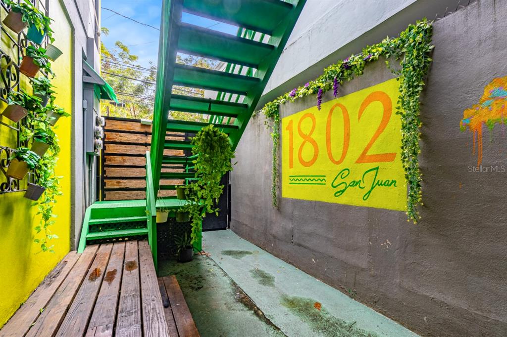 A green metal staircase leads to an outdoor area with a painted address sign — 1802 AVE FERNANDEZ JUNCOS, SAN JUAN, PR