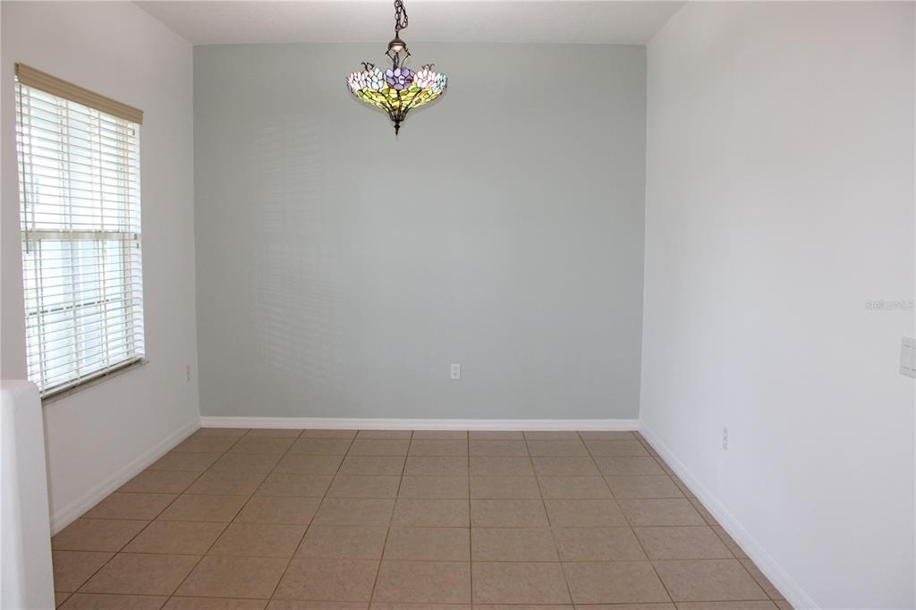An empty dining room features light blue walls, tile flooring, and a stained-glass chandelier — 339 MARINERS GATE DRIVE, EDGEWATER, FL