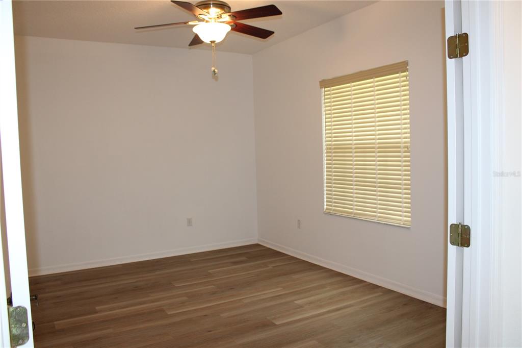 An empty bedroom features light-colored walls, wood-look flooring, a ceiling fan, and a window — 339 MARINERS GATE DRIVE, EDGEWATER, FL