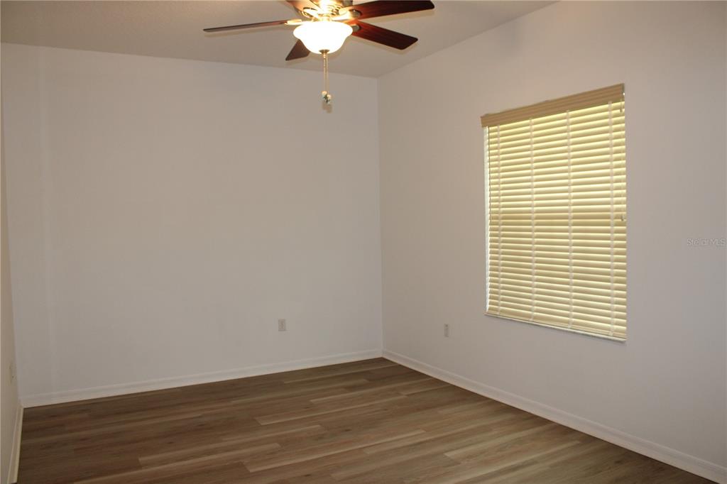 An empty bedroom features light-colored walls, wood-look flooring, a ceiling fan, and a window — 339 MARINERS GATE DRIVE, EDGEWATER, FL