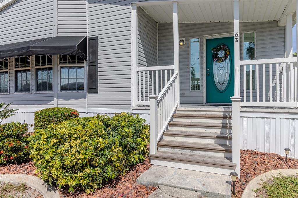 The exterior of a house features gray siding, a teal front door, and wooden steps — 2100 KINGS HIGHWAY UNIT 63, PORT CHARLOTTE, FL