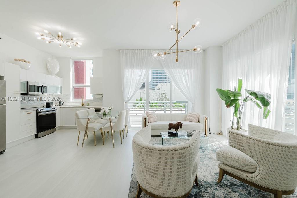 A bright, open-concept living and dining area features white cabinetry, modern lighting, and floor-to-ceiling windows — 133 NE 2nd Ave # 512, Miami FL 33132, MIAMI, FL