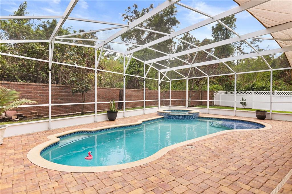 A screened-in swimming pool and hot tub with brick pavers and a brick wall — 10180 CYPRESS VINE DRIVE, ORLANDO, FL