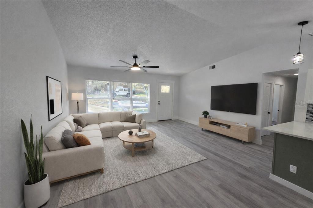A living room features light gray flooring, a sectional sofa, a coffee table, and television — 34071 MADISON AVENUE, DADE CITY, FL