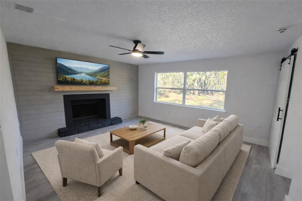 A living room features a fireplace with a shiplap wall, wood flooring, and neutral furniture — 34071 MADISON AVENUE, DADE CITY, FL
