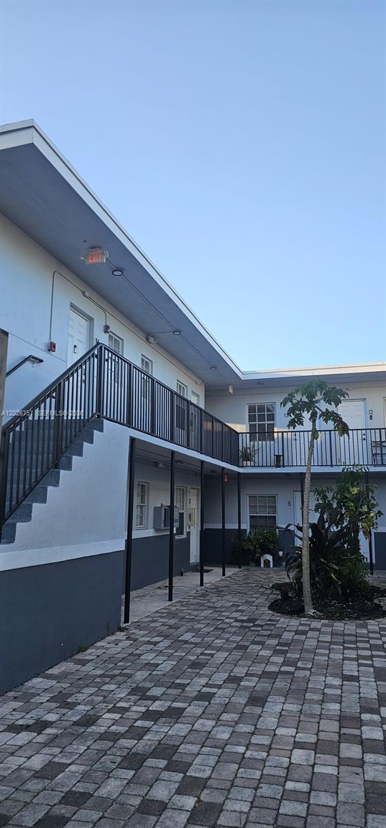 An exterior view of a two-story apartment building with a paved courtyard and metal railings — 3615 Thomas Ave # 13, Miami FL 33133, MIAMI, FL
