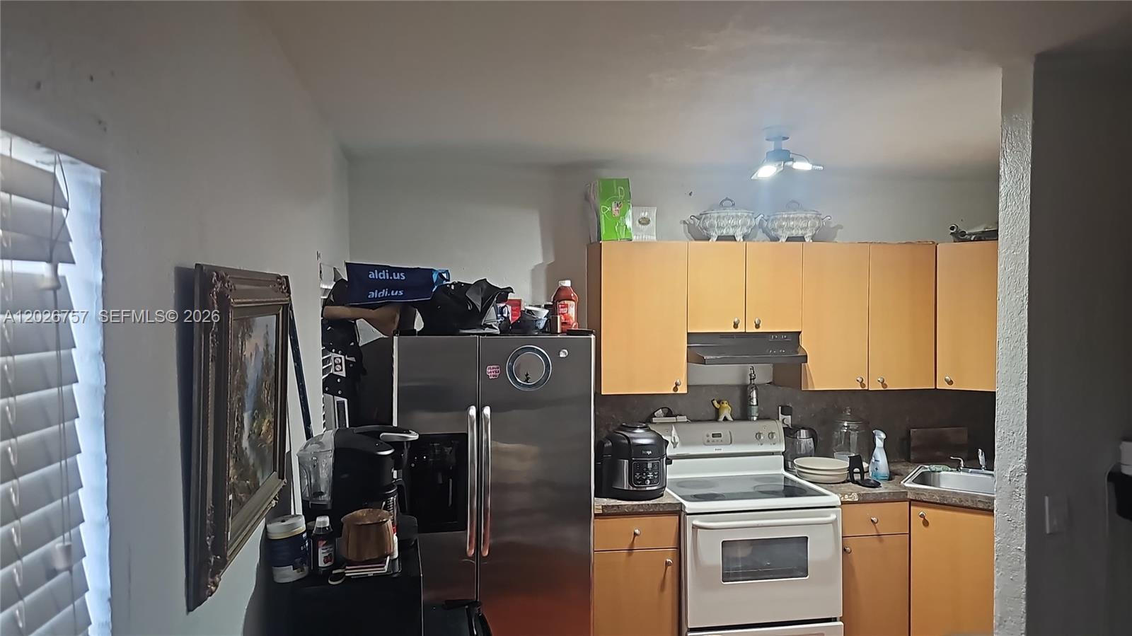 A kitchen features light wood cabinets, stainless steel appliances, and a white electric stove — 3615 Thomas Ave # 13, Miami FL 33133, MIAMI, FL