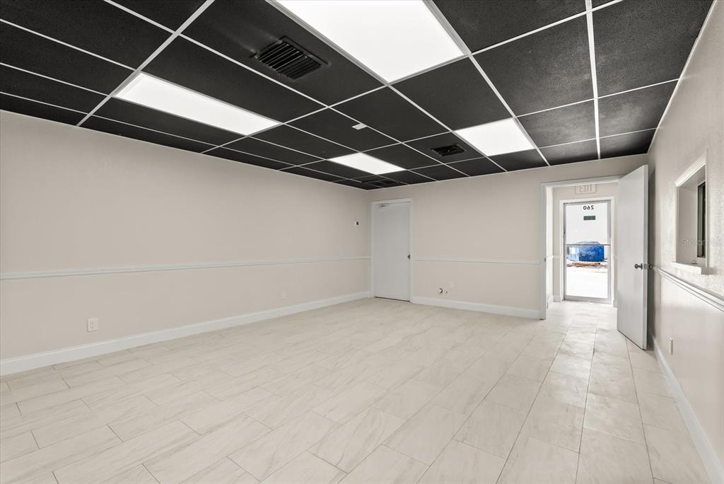 An empty office space features a black drop ceiling, recessed lighting, and light-colored tile flooring — 260 POWER COURT UNIT 100-150, SANFORD, FL