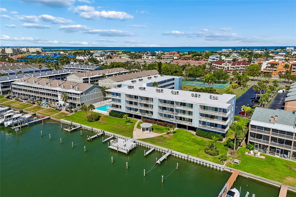 An aerial view shows a multi-story waterfront condominium complex with a pool and boat docks — 719 PINELLAS BAYWAY S UNIT 301, ST PETERSBURG, FL