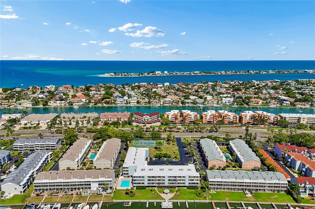 An aerial view shows a multi-building apartment complex with pools and a nearby waterfront — 719 PINELLAS BAYWAY S UNIT 301, ST PETERSBURG, FL