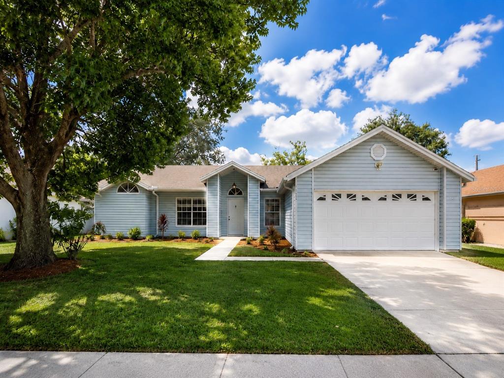 A light blue single-story house with a white garage door and a large front tree — 5113 TIMBER RIDGE TR, OCOEE, FL