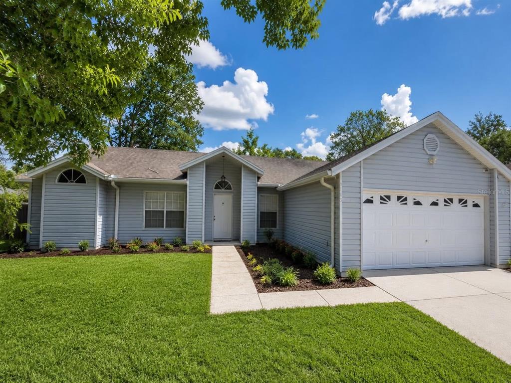 A single-story house with light blue siding, a white garage door, and a front walkway — 5113 TIMBER RIDGE TR, OCOEE, FL