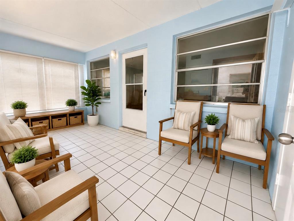 A sunroom with light blue walls, white tiled floors, and several wooden armchairs — 3100 HARTFORD STREET N UNIT 114, ST PETERSBURG, FL