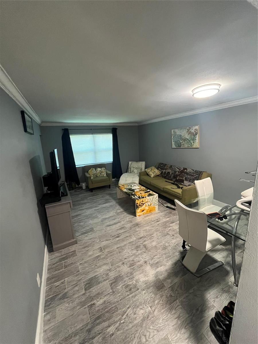 A living room with gray walls, wood-look tile flooring, a sofa, and a dining set — 4364 NW 9th Avenue # 1d, Deerfield Beach FL 33064, DEERFIELD BEACH, FL