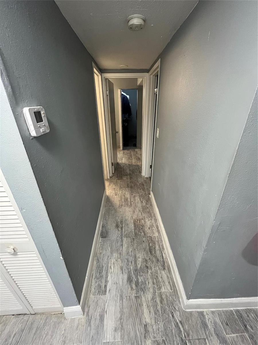 A narrow hallway with gray walls and wood-look tile flooring leads to two doorways — 4364 NW 9th Avenue # 1d, Deerfield Beach FL 33064, DEERFIELD BEACH, FL