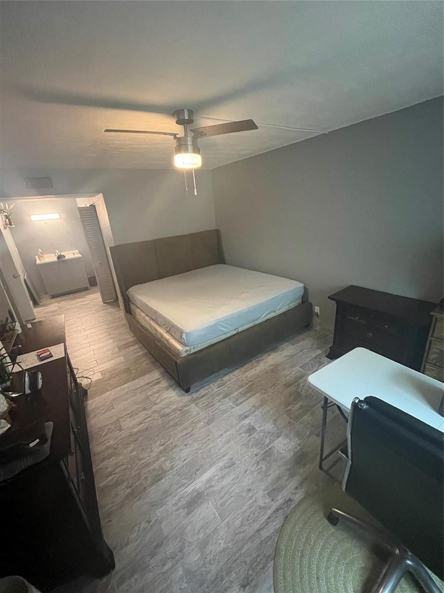 A bedroom features a brown upholstered bed, gray walls, wood-look tile flooring, and a ceiling fan — 4364 NW 9th Avenue # 1d, Deerfield Beach FL 33064, DEERFIELD BEACH, FL