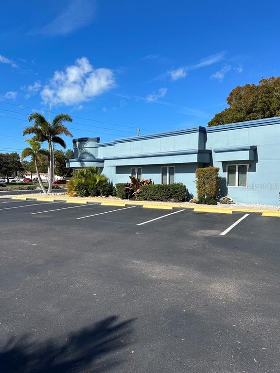 A blue commercial building with a parking lot and palm trees under a clear sky — 7641 66TH STREET N, PINELLAS PARK, FL