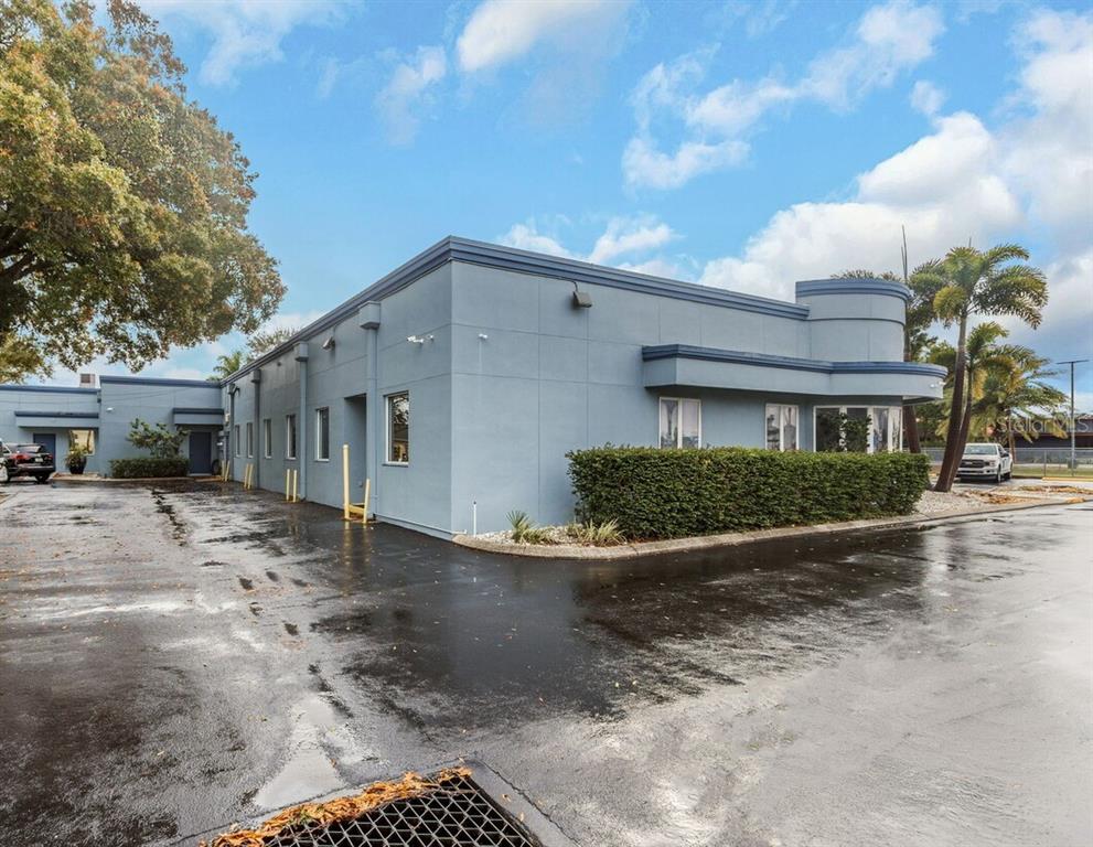 A light blue commercial building with a curved corner and a paved parking lot — 7641 66TH STREET N, PINELLAS PARK, FL