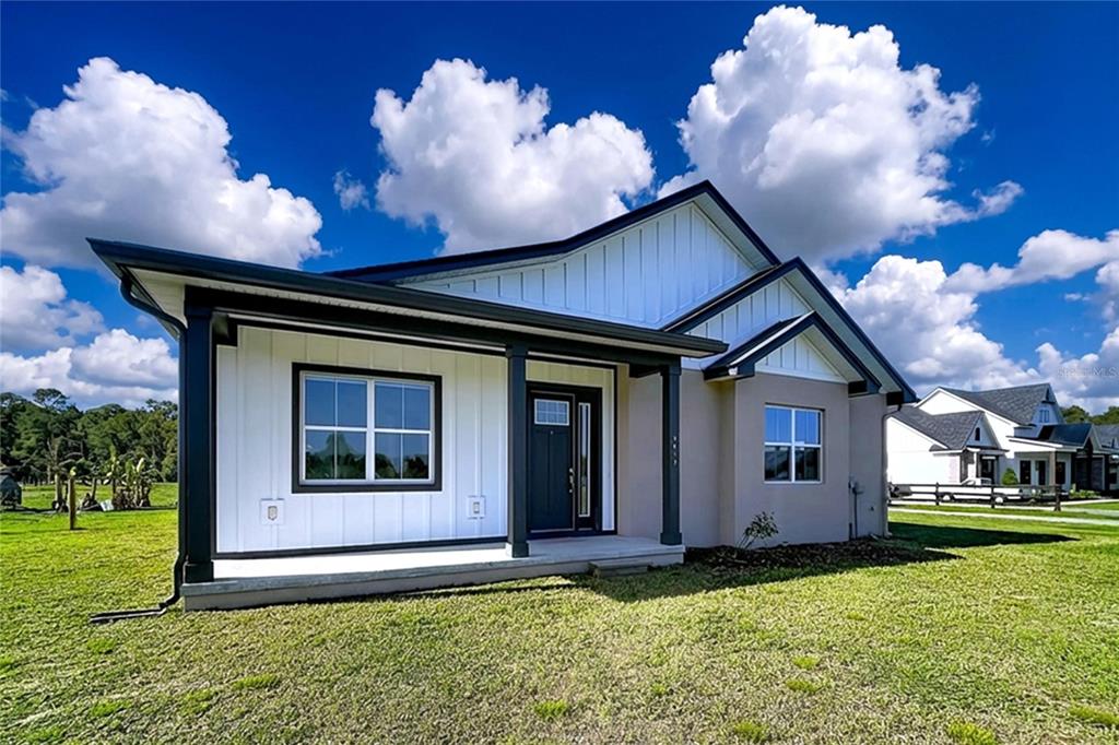 A modern single-story house with white vertical siding, a dark front door, and a covered porch — 3063 ENGLISH ROAD, PLANT CITY, FL