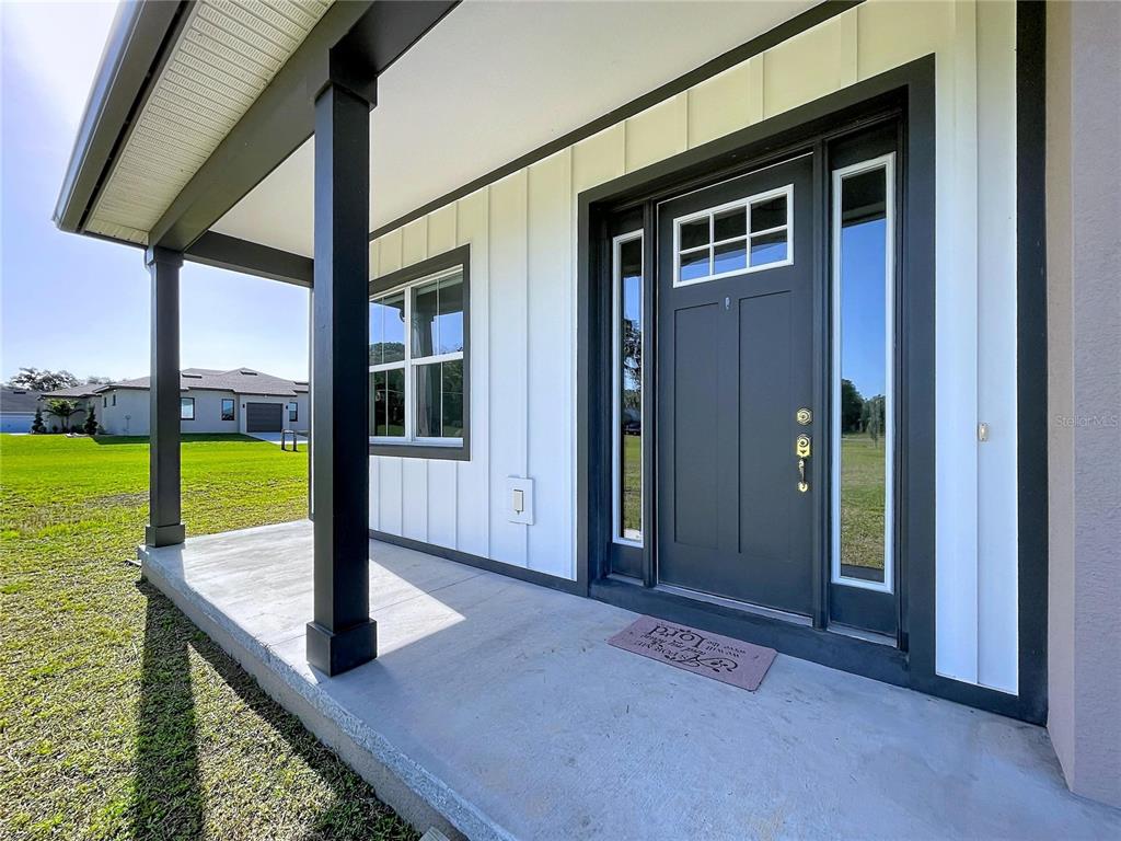 A covered front porch with a dark gray door and white board-and-batten siding — 3063 ENGLISH ROAD, PLANT CITY, FL