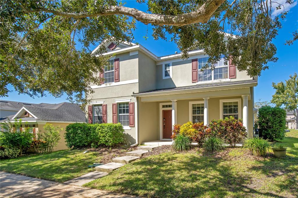 A two-story house with tan stucco siding, red shutters, and a covered front porch — 2053 NOBSCOT PLACE, APOPKA, FL