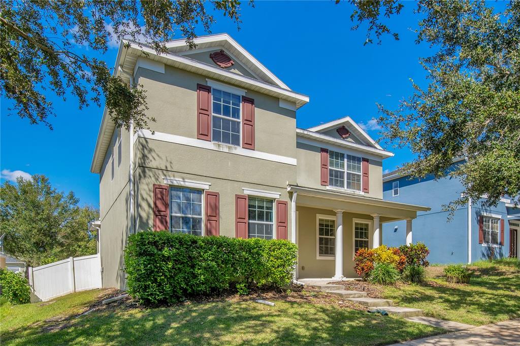 A two-story house with light green stucco siding, dark shutters, and a covered front porch — 2053 NOBSCOT PLACE, APOPKA, FL