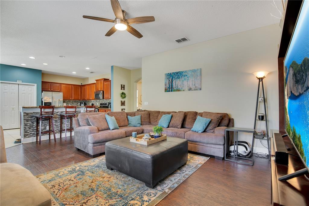 A living room with a brown sectional, large ottoman, and an open kitchen with bar seating — 2053 NOBSCOT PLACE, APOPKA, FL