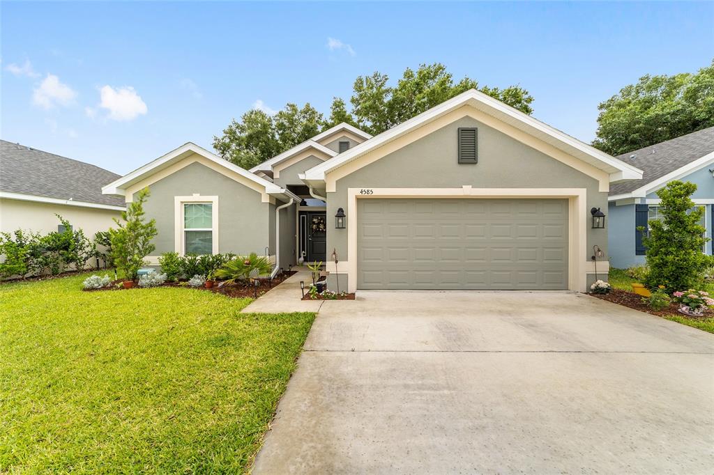 A single-story house with a light green exterior, a two-car garage, and a front lawn — 4585 SE 25TH LOOP, OCALA, FL