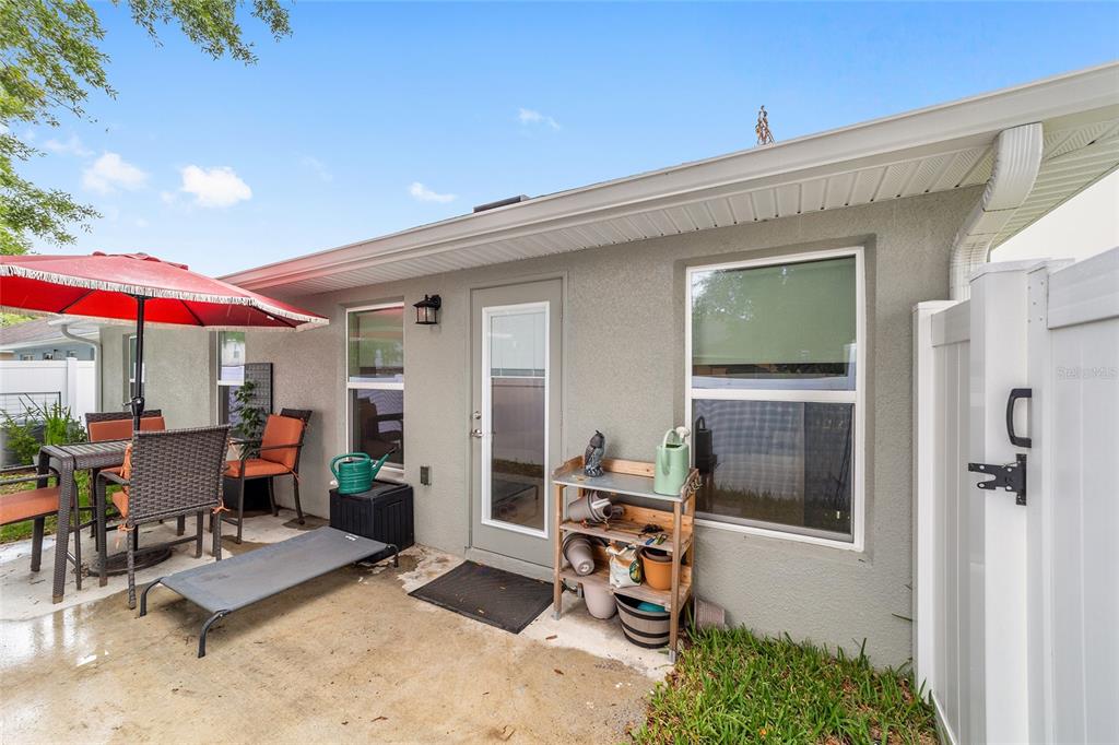 A concrete patio features outdoor furniture, a red umbrella, and a wooden potting shelf — 4585 SE 25TH LOOP, OCALA, FL