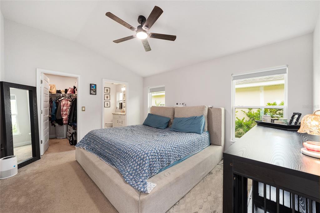 A bedroom features a bed with a blue quilt, a ceiling fan, and an attached closet — 4585 SE 25TH LOOP, OCALA, FL