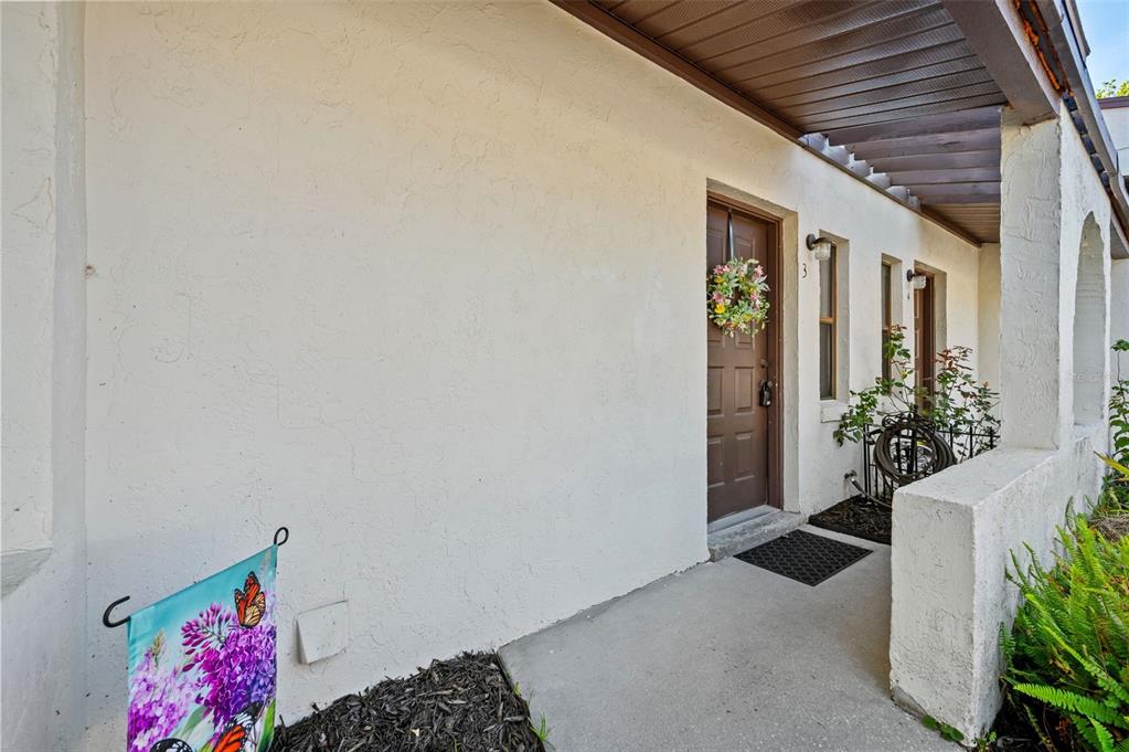 A covered concrete walkway leads to a brown front door with a floral wreath — 2635 SW 35TH PLACE UNIT 1903, GAINESVILLE, FL