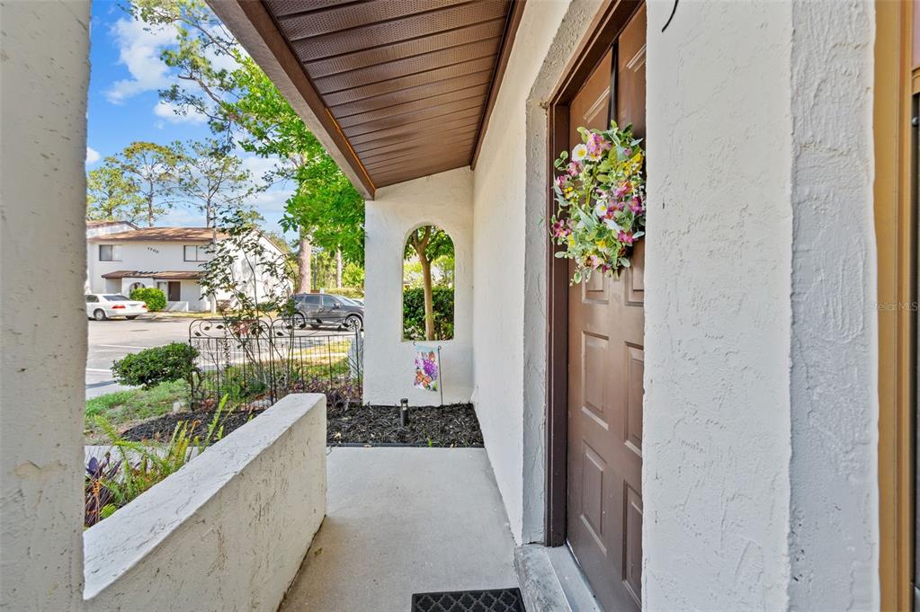 A covered entryway features a brown front door with a floral wreath and stucco walls — 2635 SW 35TH PLACE UNIT 1903, GAINESVILLE, FL
