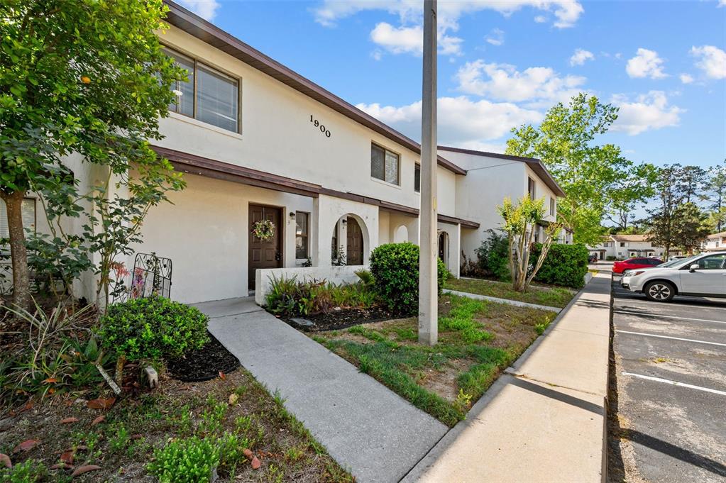 A two-story townhouse exterior features a concrete walkway, a brown front door, and parking spaces — 2635 SW 35TH PLACE UNIT 1903, GAINESVILLE, FL