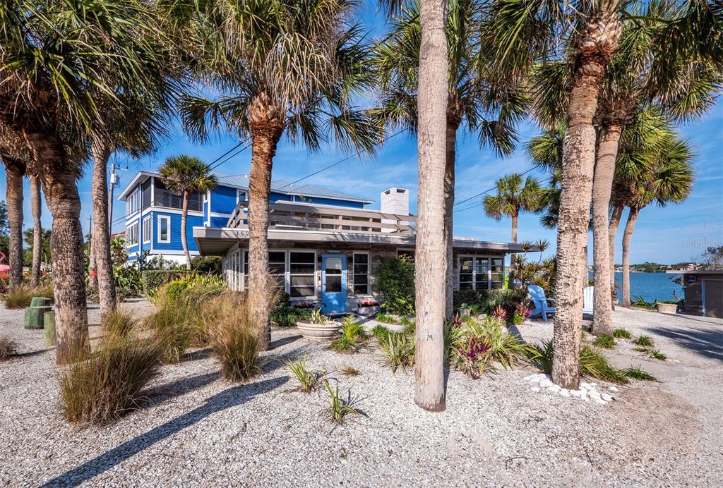 A single-story house with a flat roof and blue door sits among palm trees — 1620 CASEY KEY ROAD, NOKOMIS, FL