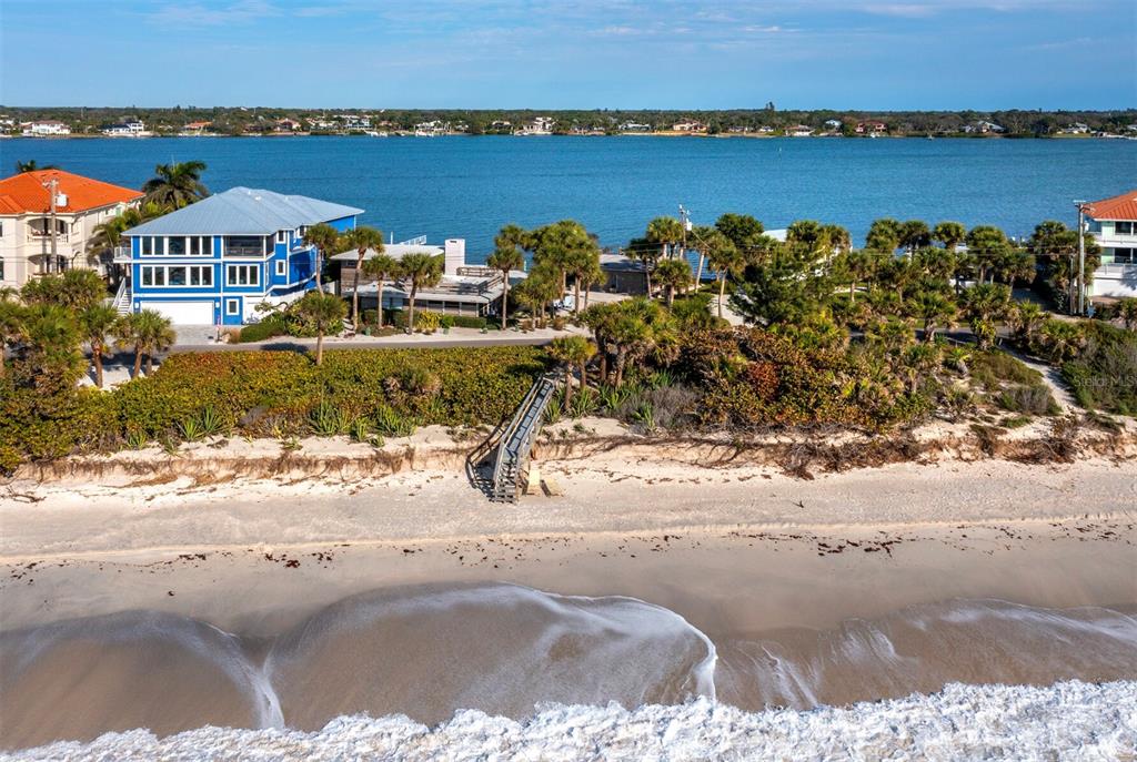 An aerial view shows a beach with a wooden staircase leading to a coastal house — 1620 CASEY KEY ROAD, NOKOMIS, FL