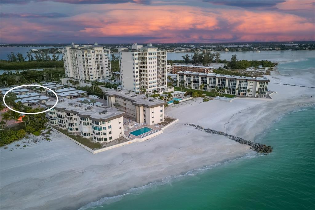 An aerial view shows a coastal residential complex with a circled single-story building and tennis courts — 1900 BENJAMIN FRANKLIN DRIVE UNIT V12, SARASOTA, FL