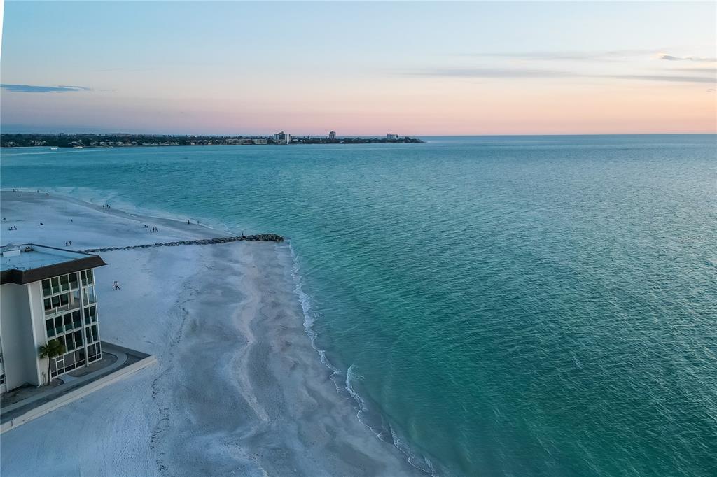 An aerial view shows a multi-story building on a white sand beach by the ocean — 1900 BENJAMIN FRANKLIN DRIVE UNIT V12, SARASOTA, FL