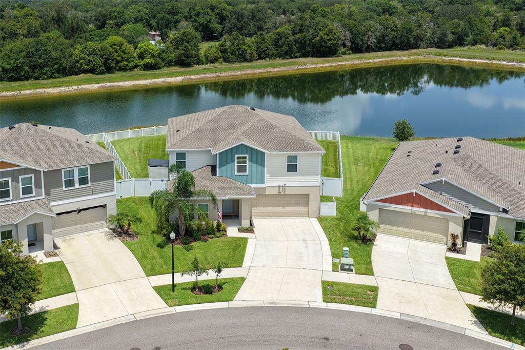 An aerial view shows three suburban houses with driveways facing a cul-de-sac and a pond — 12694 TANNENCREST DRIVE, RIVERVIEW, FL