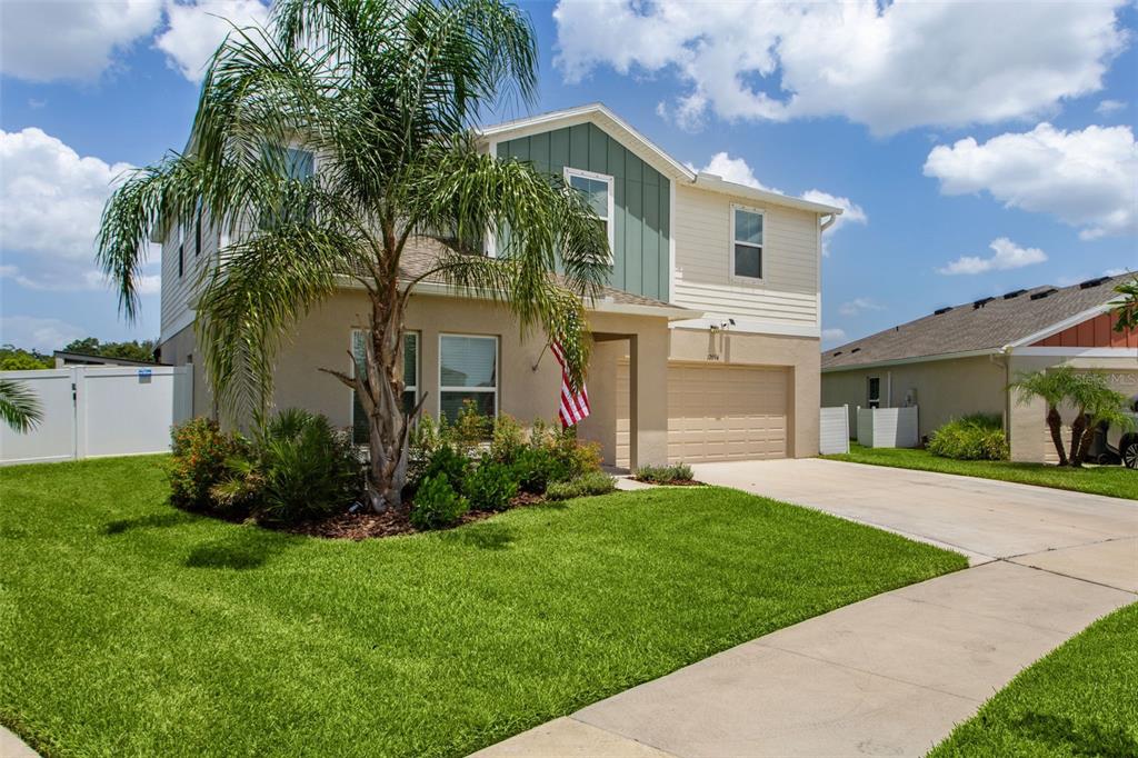 A two-story suburban house with a tan stucco exterior, green siding, and a palm tree — 12694 TANNENCREST DRIVE, RIVERVIEW, FL