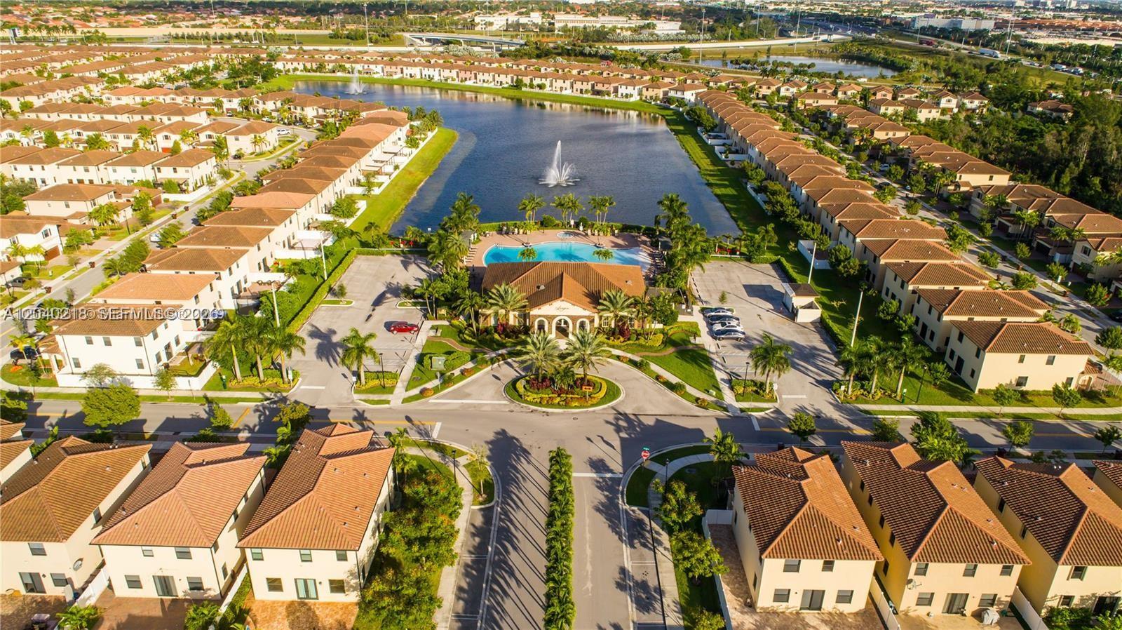 An aerial view shows a residential community with townhomes surrounding a central lake and pool — 9073 W 33rd Ave, Hialeah FL 33018, HIALEAH, FL