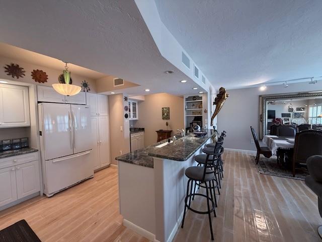 A kitchen with white cabinets, a granite breakfast bar, and light wood flooring — 3806 GULF OF MEXICO DRIVE UNIT C108, LONGBOAT KEY, FL